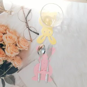 Detailed view of pink rabbit felt cutlery holder with stainless steel spoon and fork on white fur