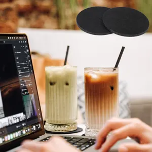 Detailed view of round black felt coasters used on a desktop with cold drinks and laptop