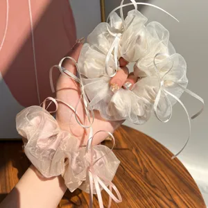 Dettaglio di eleganti elastici per capelli in rete con nastri lunghi e fiocchi rosa