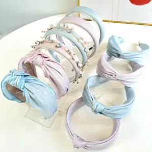 Meerdere glinsterende geknoopte stoffen haarbanden in pastelkleuren op een display