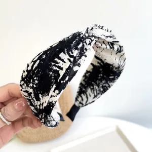 Close-up detail of a stylish knotted fabric headband with black and white tie-dye pattern.