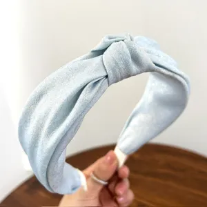 Detail van de lichtblauwe glinsterende stoffen haarband met een elegant knoopontwerp