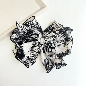 Detailed view of black and white tie-dye fabric bow hair clip with rhinestone center