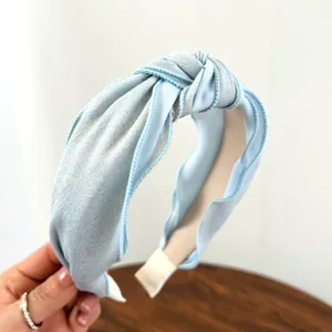Detailweergave van de fijne glittertextuur van de blauw geknoopte stoffen hoofdband.