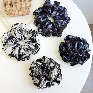Detailed view of oversized ruffled tie-dye pattern fabric scrunchies in blue and white