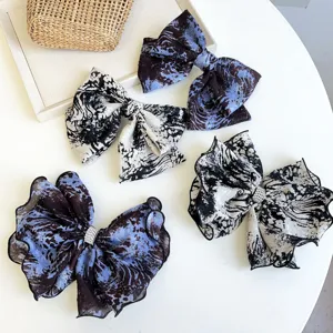 Set of four tie-dye fabric bow hair clips with rhinestone centers on white table