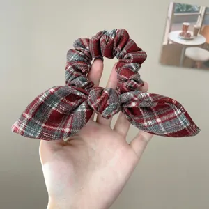Κοντινό πλάνο ενός vintage κόκκινου καρό scrunchie με φιόγκο που κρατιέται στο χέρι
