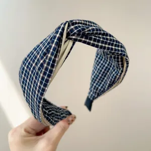 Close-up of a wide knotted headband featuring a classic blue and white plaid pattern