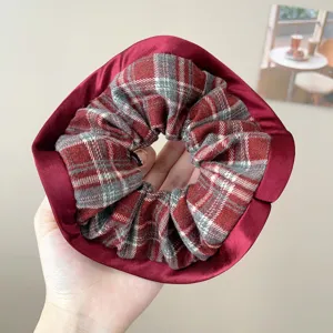 Λεπτομερής άποψη vintage κόκκινου καρό scrunchie στο χέρι που δείχνει την υφή υφάσματος.