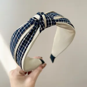 Detailed view of a wide-brimmed blue plaid knotted headband with beige fabric
