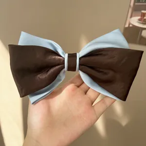 Detailed view of an elegant oversized blue and brown satin bow hair clip for women