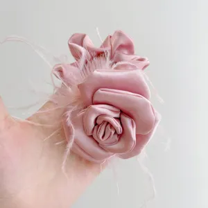 Close-up of elegant pink satin camellia hair scrunchie with ostrich feathers