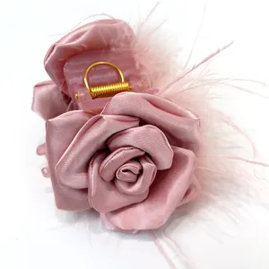 Close-up of elegant handmade pink rose hair claw clip with ostrich feather details.