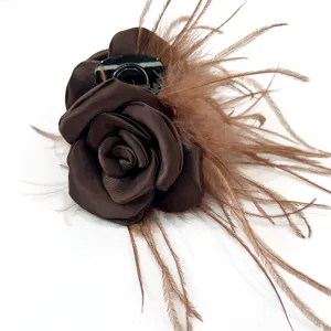 Detailed shot of brown silk rose hair claw clip with ostrich feather trim