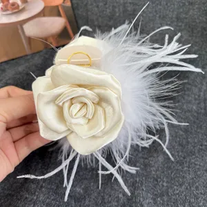 Elegant ivory camellia rose hair claw clip decorated with fluffy white ostrich feathers