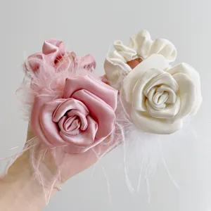 Close-up of elegant handmade satin rose hair scrunchies with soft ostrich feathers