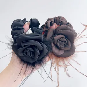 Detail view of elegant satin camellia scrunchie with soft ostrich feather trim