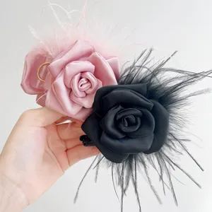 Detailed view of handmade rose hair claw clips with ostrich feathers in pink and black