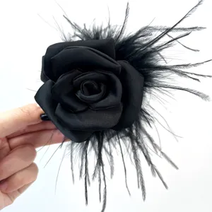 Detail macro view showing handmade black rose hair claw with ostrich feathers