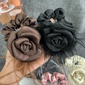 Detailed macro view of elegant satin camellia hair scrunchies with ostrich feather accents.