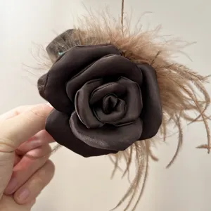 Detailed close-up of the delicate ostrich feathers and satin rose petals on the hair claw