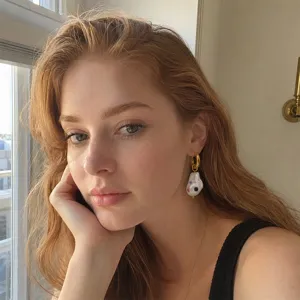 Close-up of model wearing baroque pearl earring with colorful rhinestones in gold hoop