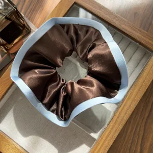 Detailed macro view of an elegant satin scrunchie in coffee brown and sea salt blue.