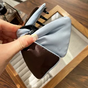 Close-up of elegant light blue and coffee brown satin bow hair claw clip texture