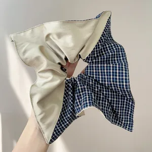 Detailed close-up view of an oversized fashion hair scrunchie in beige and blue plaid fabric