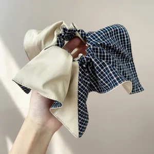 Detailed view of a wide plaid bow scrunchie featuring blue grid and beige fabric.