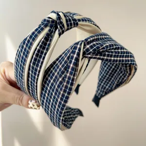 Close-up detail showing texture and knot design of navy blue plaid wide headband