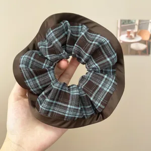 Nahaufnahme eines blau-braunen Karo-Haargummis mit einem eleganten braunen Satin-Rand