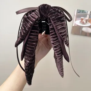 Macro view of a vintage dark brown velvet bow hair clip with textured ribbed fabric