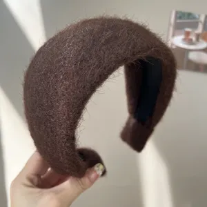 Gros plan d'un serre-tête marron duveteux montrant sa texture épaisse et son design large.