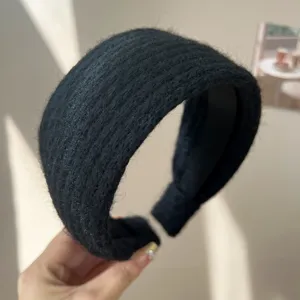Gros plan d'un serre-tête en tweed noir épais, design haut et texture antidérapante.