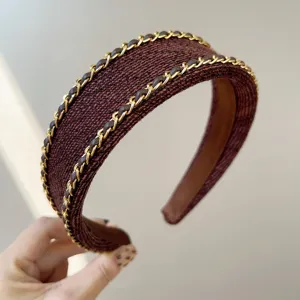 Close-up detail of Chanel style brown fabric headband with gold chain elements
