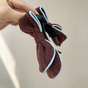 Detailed view of a brown fabric bow hair clip with elegant light blue piping decoration