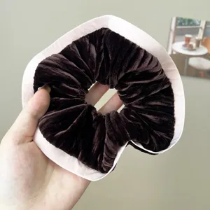 High-quality detail of a retro brown velvet scrunchie featuring an elegant light pink fabric trim