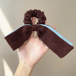 Close-up of a tweed bow hair scrunchie featuring elegant brown and blue contrast edges