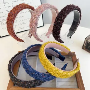 Various colors of knitted braided wide headbands displayed on clear stands and tray
