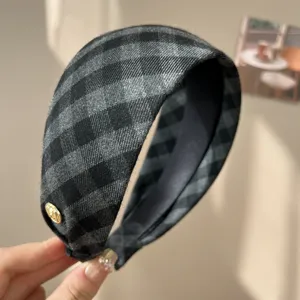 Close-up of a vintage grey and black checkered sponge headband with a gold emblem.