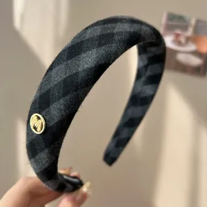 Macro view of retro gray plaid sponge headband featuring a gold M detail accessory