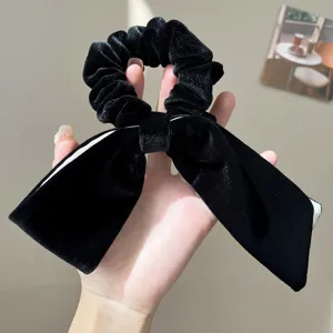 Close-up of a black velvet scrunchie featuring a large bow and subtle glitter finish