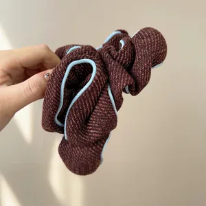 Detailed macro view of a textured brown tweed hair scrunchie with light blue piping