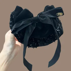 Gedetailleerd overzicht van een elegante zwarte fluwelen haarband met strik en pailletten.