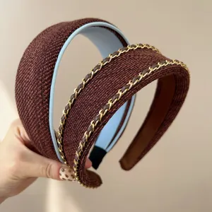 Close-up of reddish-brown wide headbands with elegant gold chain and leather detail