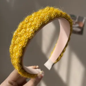 Close-up of a handmade yellow knitted braided wide headband with thick yarn texture
