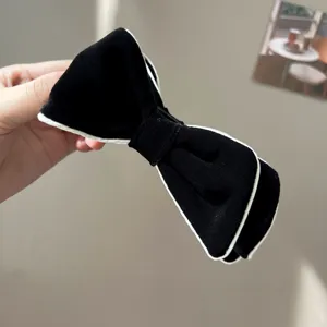 Elegant black velvet bow hair clip with white piping detail for women.