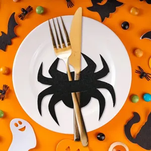 Macro view of black felt spider cutlery holder on white plate with Halloween decor