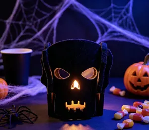 Détail d'un bougeoir en feutre noir en forme de crâne avec une lumière chaude d'Halloween